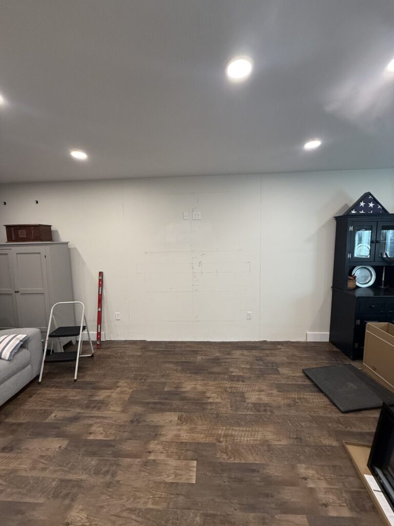 Bare white living room wall with a pencil layout marked out for a fireplace and TV, before any framing began