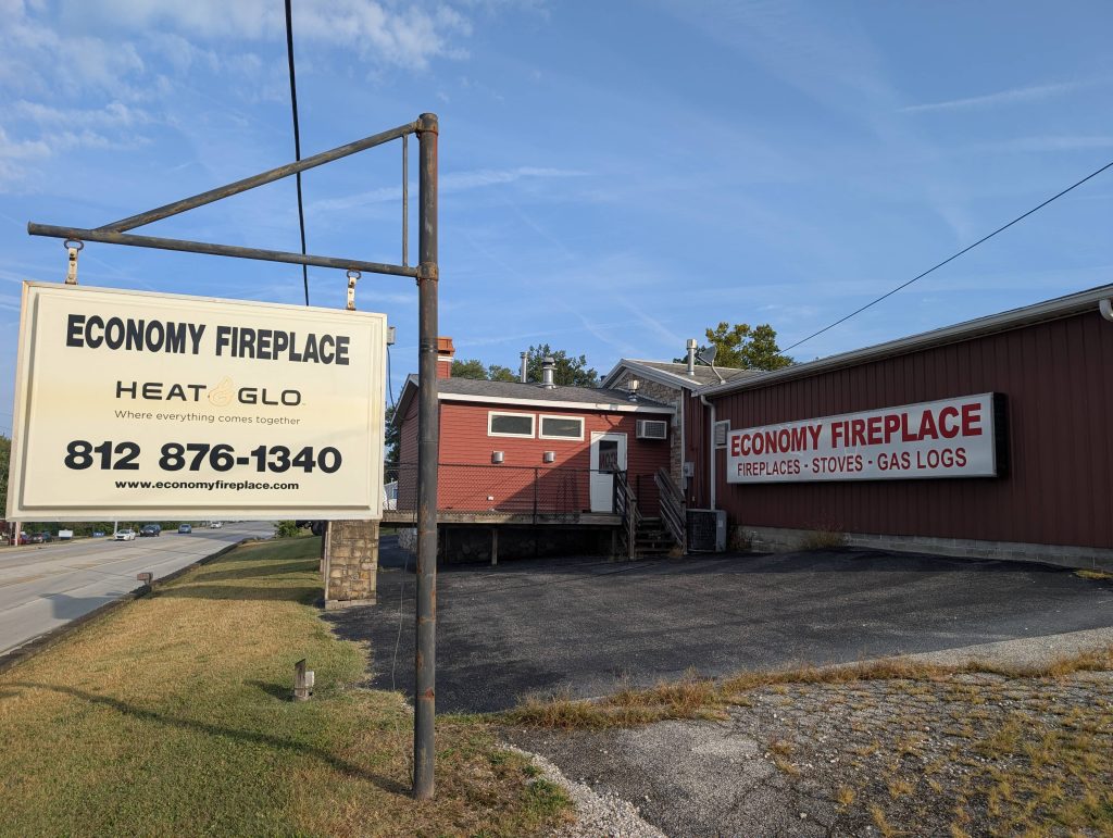 Exterior view of Economy Fireplace, Inc. in Bloomington, Indiana, featuring store signage and a red commercial building on a clear morning