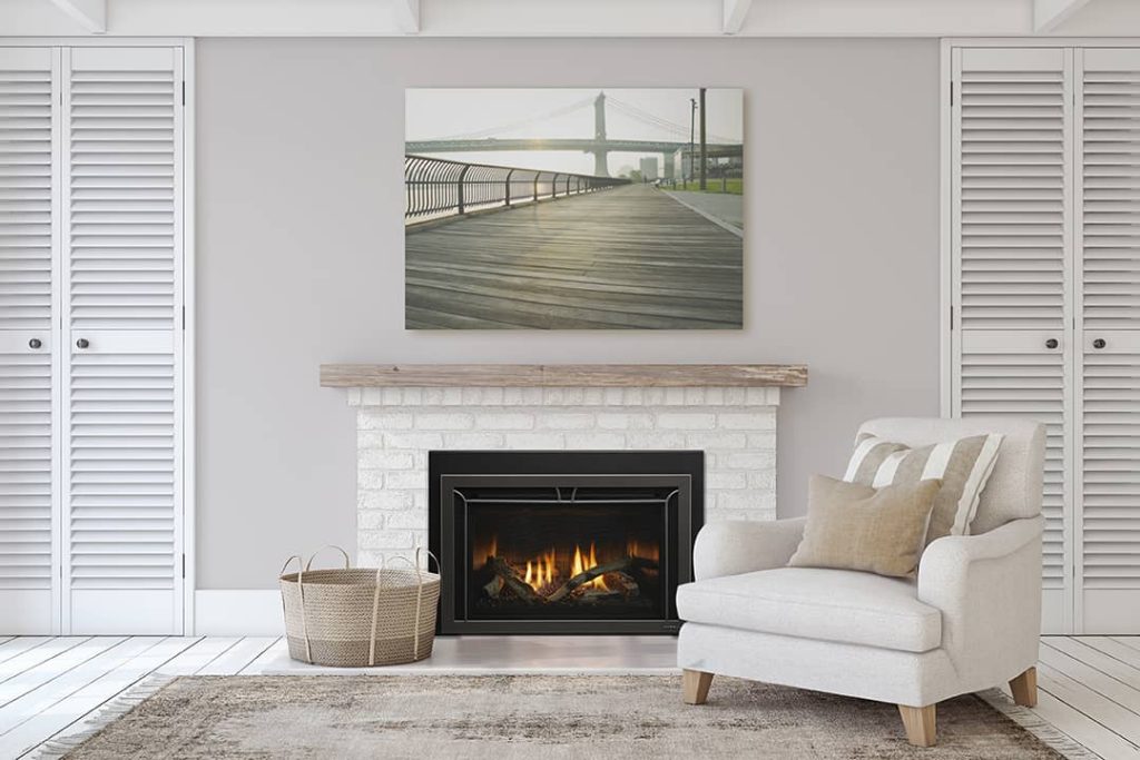 Gas fireplace insert with glowing flames and embers, installed in a white brick mantel in a cozy neutral-toned living room with modern decor