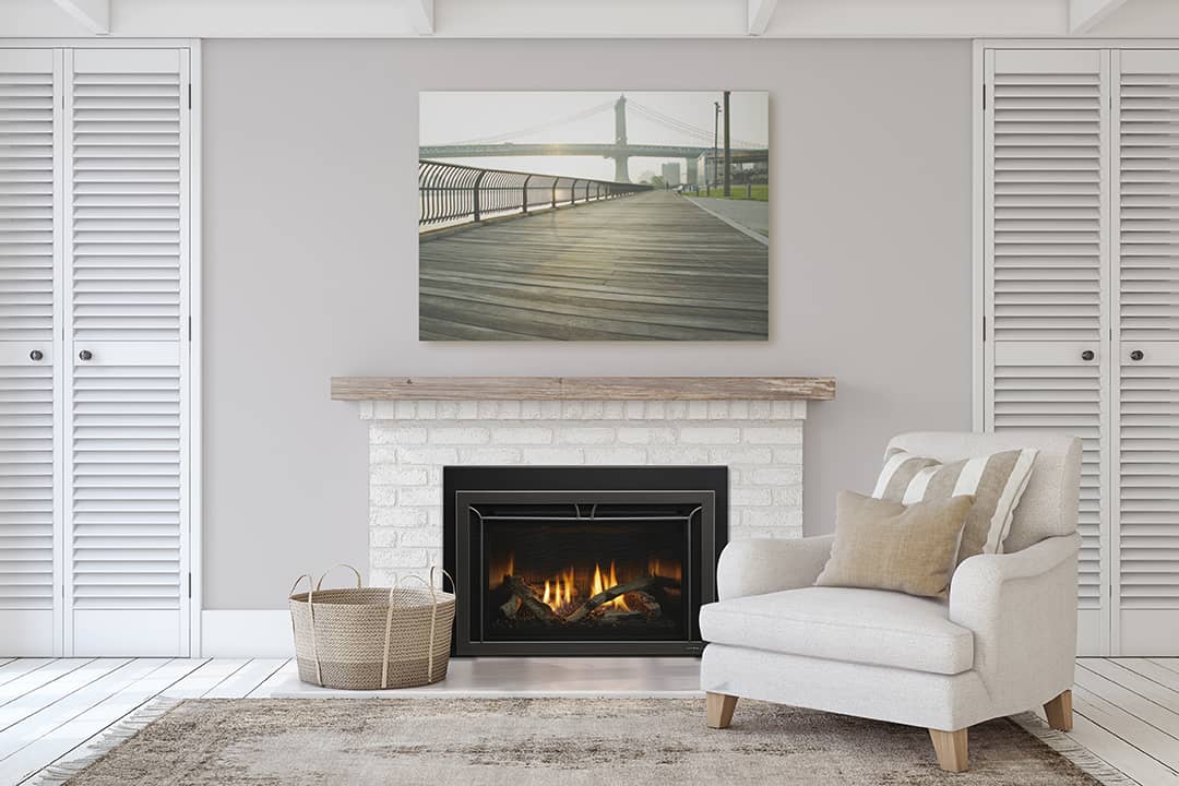 Gas fireplace insert with glowing flames and embers, installed in a white brick mantel in a cozy neutral-toned living room with modern decor
